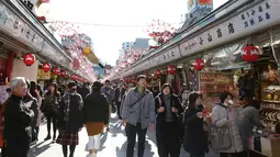 Pejalan kaki melintas di bawah dekorasi shio babi tanah yang mengarah ke kuil Buddha Asakusa Sensoji di Tokyo, Jepang, Kamis (27/12). Tahun 2019 dipercaya menjadi waktu yang tepat untuk menghasilkan uang dan berinvestasi. (AP Photo/Koji Sasahara)