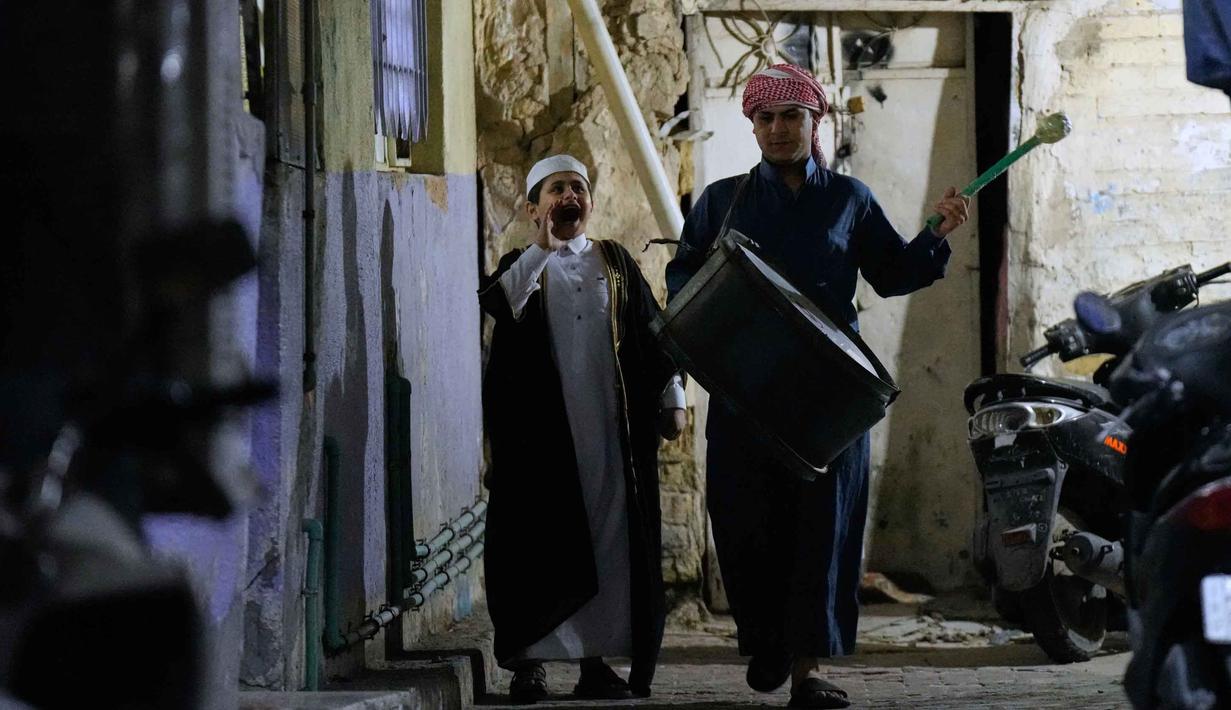Wissam Ali (kanan), seorang "mesaharati" atau penyeru subuh berusia 22 tahun, saat membangunkan orang-orang untuk makan sebelum matahari terbit, selama bulan suci Ramadan, di lingkungan miskin distrik Fadhil di Baghdad, Irak, Senin 23 Februari 2026. Mesaharati (juga dikenal sebagai Al-Mesaharati) merupakan sebutan bagi seseorang yang bertugas membangunkan umat Muslim untuk makan sahur sebelum waktu Subuh tiba selama bulan Ramadan. (AP Photo/Hadi Mizban)