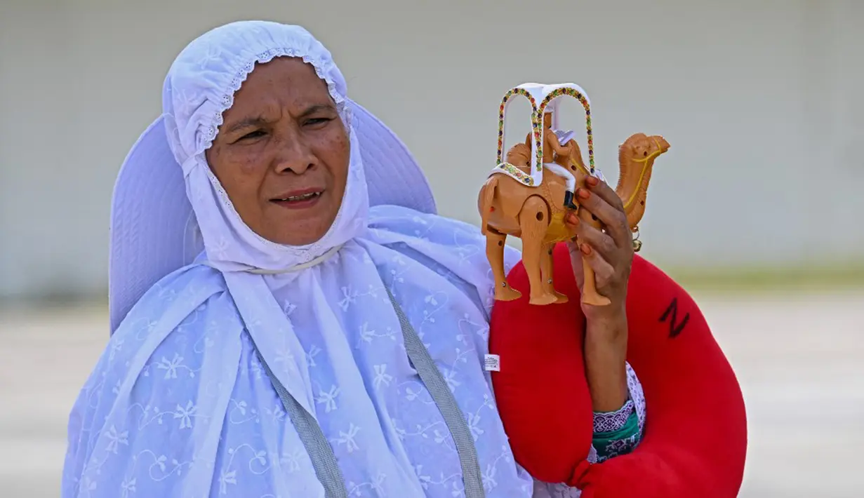Seorang jemaah haji membawa mainan saat tiba di Bandara Internasional Sultan Iskandar Muda, Blang Bintang, Aceh, Senin (31/7/2023). Sebanyak 254 jemaah haji Aceh yang tergabung dalam kelompok terbang (kloter) 12 atau kloter terakhir sudah di tiba di Aceh pada siang ini. (Chaideer MAHYUDDIN/AFP)