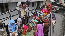Perempuan dan anak-anak menaiki mobil bak terbuka untuk dievakuasi dari rumah mereka di lereng Gunung Merapi, di Krinjing, Jawa Tengah, Jumat (6/11/2020). Evakuasi dilakukan bagi warga lereng Merapi menyusul peningkatan status aktivitas vulkanik gunung tersebut. (AP Photo/Taufiq Rozzaq)