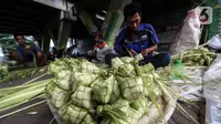 Perajin membuat kulit ketupat dari janur saat berdagang di Pesanggrahan, Jakarta, Kamis (20/4/2023). (Liputan6.com/Johan Tallo)