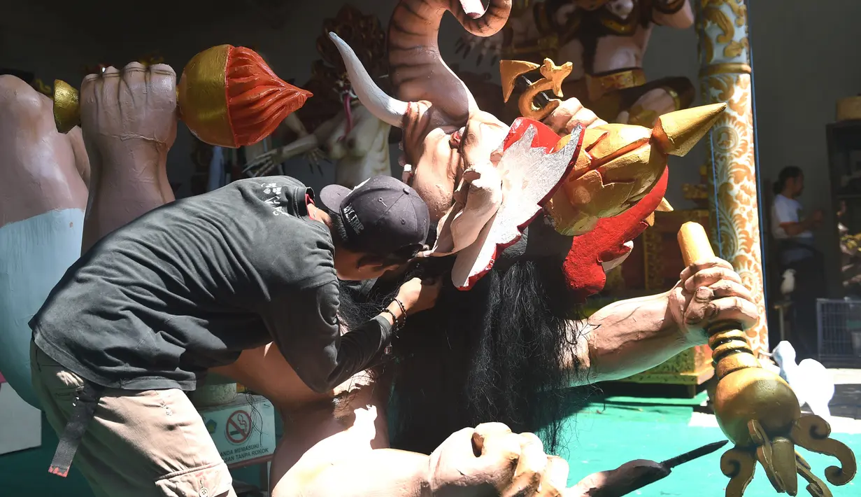 Seorang seniman memasangkan rambut saat menyelesaikan pembuatan patung atau yang dikenal ogoh-ogoh sebelum Perayaan Nyepi di Denpasar, Bali (12/3). (AFP Photo/Sonny Tumbelaka)