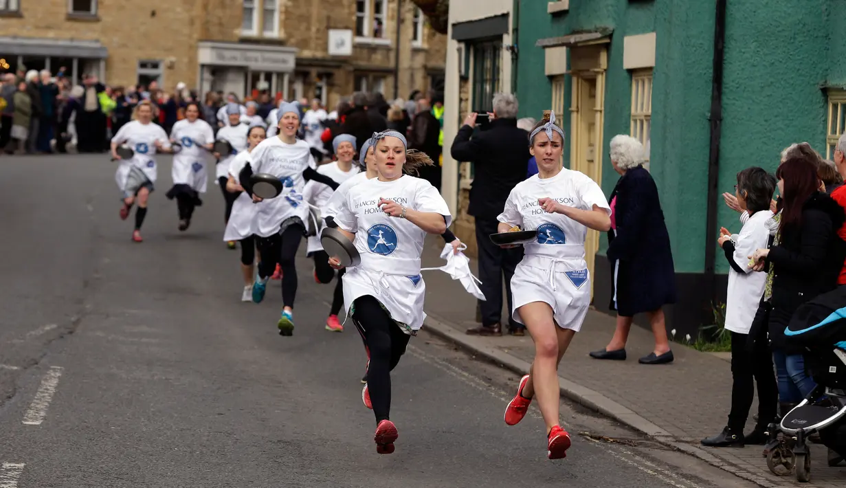 Para peserta bersaing dalam lomba lari sembari membawa wajan berisi pancake di Kota Olney, Buckinghamshire, Inggris, Selasa (28/2). Tidak hanya membawa wajan, peserta juga harus membolak-balikan pancake sambil tetap berlari.  (AP Photo/Alastair Grant)
