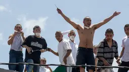 Sekelompok narapidana remaja berdiri diatap saat kerushuan di penjara Juvenile Gaviotas di Guatemala City, Guatemala (3/7). Akibat kerusuhan tersebut, 10 narapidana remaja dilaporkan melarikan diri dari penjara. (AP Photo / Moises Castillo)