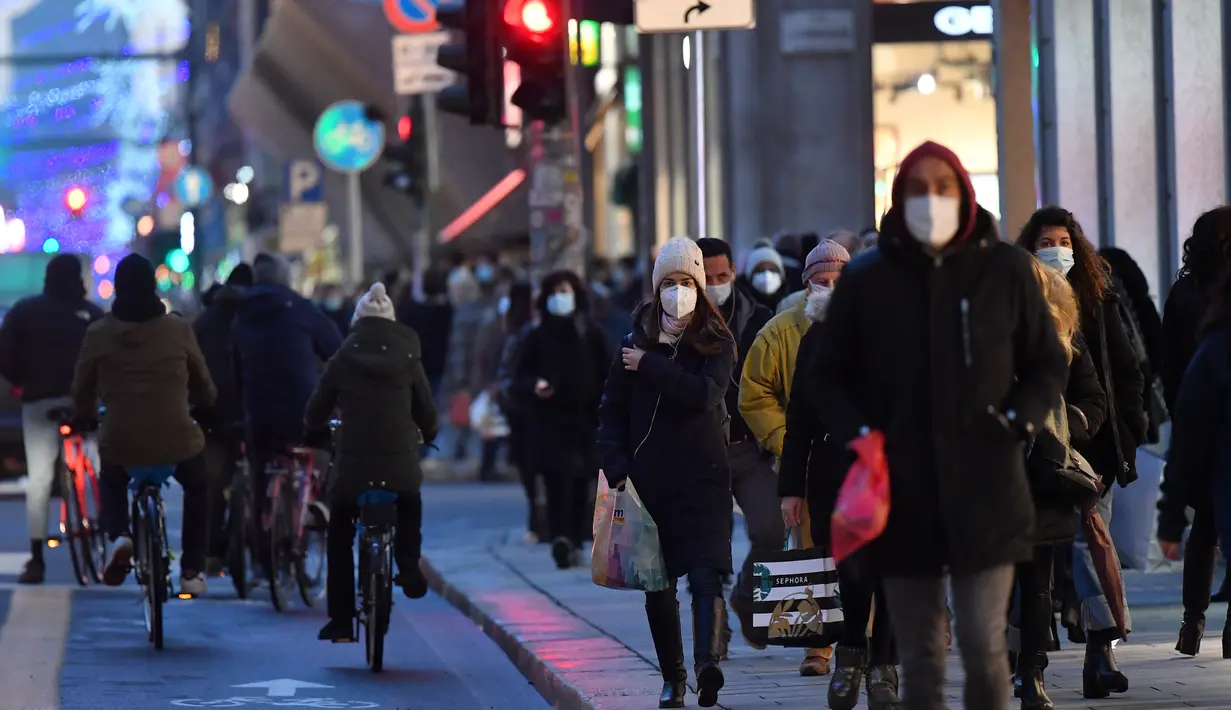 Orang-orang berjalan di sebuah jalan sembari menenteng tas belanjaan menjelang Natal di Milan, Italia, pada 7 Desember 2020. Italia mencatat 13.720 infeksi baru Covid-19 pada Senin (7/12) dan merupakan penambahan harian terendah sejak 20 Oktober lalu, yang mencapai 10.874 infeksi baru. (Xinhua/Danie