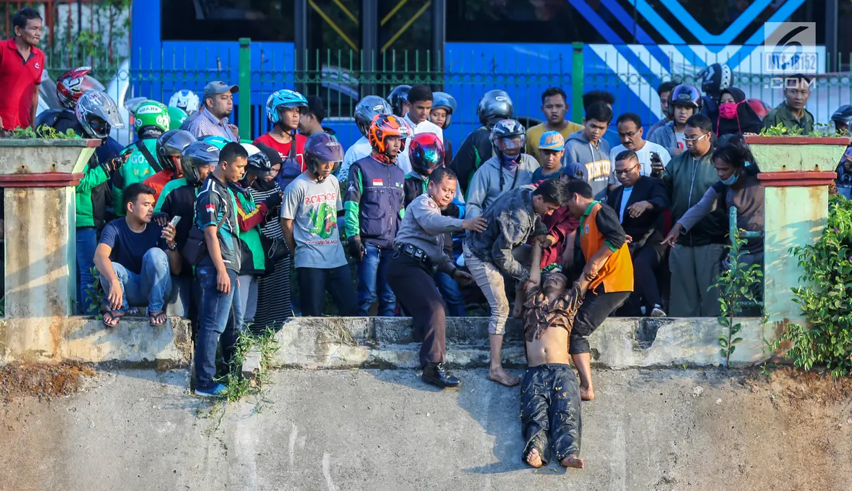 Polisi dan warga mengamankan terduga pelaku pelecehan seksual yang menceburkan diri di Kali Ciliwung, Manggarai, Jakarta, Minggu (7/6/2019). Pelaku dikejar massa usai melakukan pelecehan dengan modus mencegat korban perempuan mendapat hadiah dari sayembara televisi. (Liputan6.com/Fery Pradolo)