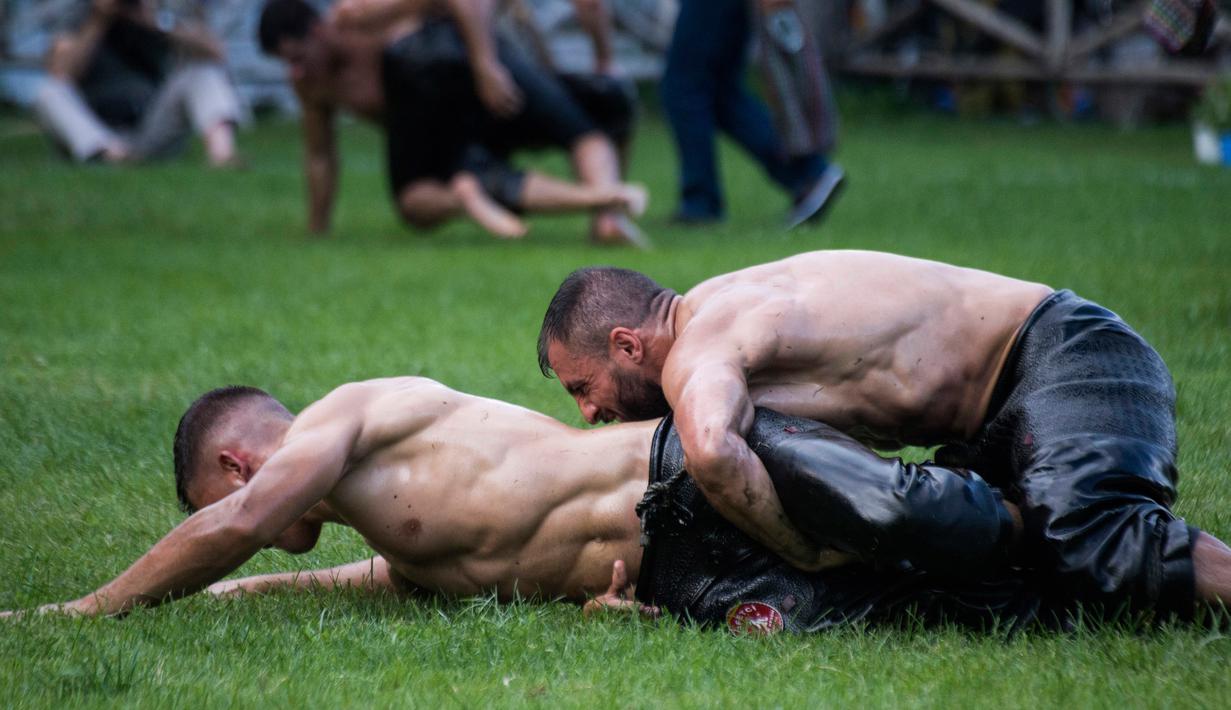Pegulat saling kunci dengan lawannya dalam kompetisi tahunan gulat minyak tradisional di Sochos, Yunani, 30 Juni 2018. Pertandingan perpaduan tradisi Yunani kuno dan zaman modern itu diiringi musik tradisional. (AP/Giannis Papanikos)