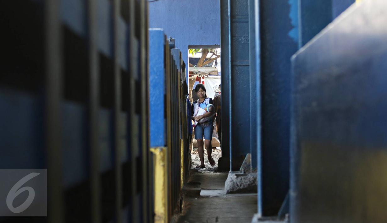 Warga melintasi jalan setapak di pintu air Petamburan, Jakarta, Jumat (17/2). Warga terpaksa melewati pintu air karena tidak ada jembatan penyeberangan orang di kawasan tersebut. (Liputan6.com/Immanuel Antonius)