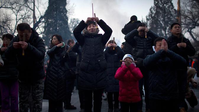 Orang-orang memegang dupa saat berdoa di Kuil Lama di Beijing (5/2). Orang-orang China merayakan hari pertama Tahun Baru Imlek pada hari Selasa, Tahun Babi di zodiak Tiongkok dengan berdoa di kuil. (AP Photo/Mark Schiefelbein)