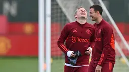 Pemain Manchester United, Donny van de Beek dan Jonny Evans, tertawa lepas saat sesi latihan di Carrington Training Complex, Senin (23/10/2023). Skuad Setan Merah tampak lepas saat sesi latihan kali ini. (AFP/Paul Ellis)