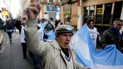 Sekelompok pensiunan berbaris sambil memegang bendera Argentina menuju Plaza de Mayo, Buenos Aires, Argentina, Selasa (22/8).  Mereka terdiri dari para pekerja dan pensiunan yang melawan kebijakan ekonomi Presiden Mauricio Macri. (Victor R. Caivano/AP)