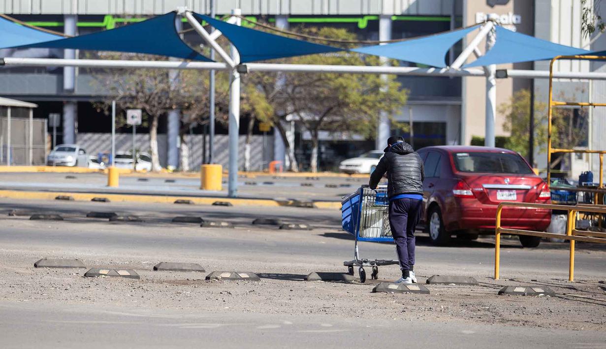 El Mencho tewas saat dalam perjalanan udara menuju Mexico City. Tampak dalam foto, seorang pria mendorong troli belanja melalui tempat parkir sebuah toko yang tutup di Morelia, negara bagian Michoacan, Meksiko, pada 23 Februari 2026. (Enrique Castro/AFP)