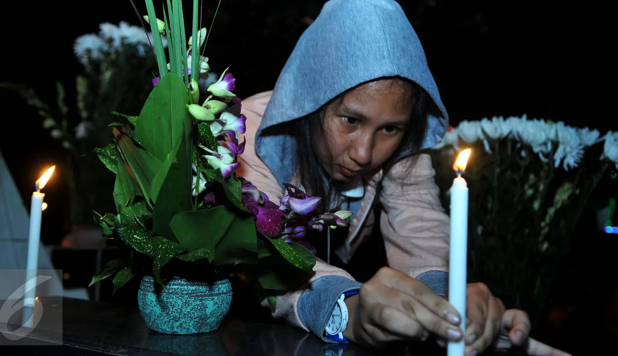Warga keturunan Portugis menyalakan lilin saat ziarah ke makam yang terdapat di sebelah Gereja Tugu, Jakarta, Kamis (24/12). Tradisi nyekar itu dilakukan usai mengikuti ibadah kebaktian malam Natal di gereja. (Liputan6.com/Gempur M Surya)