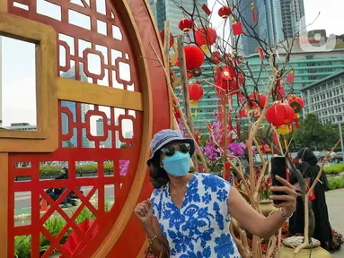 Warga berswafoto di depan ornamen dengan nuansa Imlek di kawasan Bundaran HI, Jakarta, Sabtu (29/1/2022). Ornamen yang didominasi warna merah dan emas ini dipasang dalam rangka menyambut perayaan Tahun Baru Imlek 2573, yang jatuh pada 1 Februari mendatang. (Liputan6.com/Herman Zakharia)
