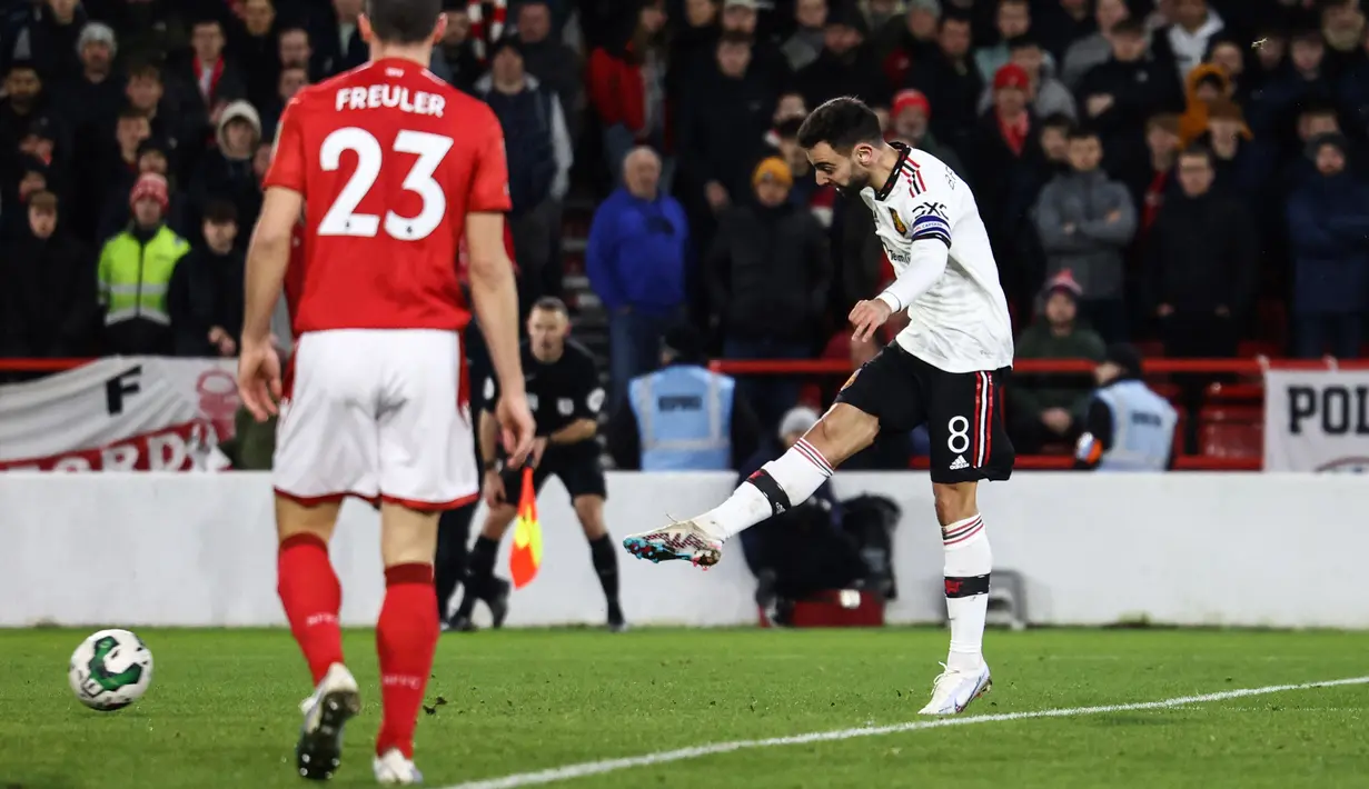 Pemain Manchester United, Bruno Fernandes (kanan) menendang bola ke gawang Nottingham Forrest dan mengonversi menjadi gol di menit ke-89 dalam semi final leg pertama Carabao Cup 2022/2023 di The City Ground, Kamis (26/1/2023). (AFP/Darren Staples)