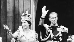 Dalam file foto ini diambil pada tanggal 2 Juni 1953 Ratu Inggris Elizabeth II (kiri) ditemani oleh Pangeran Philip dari Inggris, Duke of Edinburgh (kanan) melambai ke kerumunan, setelah dinobatkan di Westminter Abbey di London. (Photo by INTERCONTINENTALE / AFP)