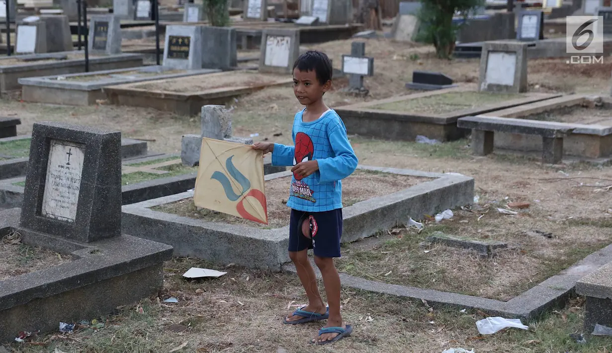 Seorang anak bermain layangan di TPU Menteng Pulo, Jakarta, Kamis (18/10). Padatnya pemukiman penduduk serta gedung bertingkat di kawasan tersebut menyebabkan anak-anak terpaksa bermain di tempat yang tidak semestinya. (Liputan6.com/Immanuel Antonius)