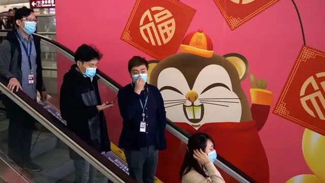 Orang-orang memakai masker saat menaiki eskalator di Bandara Internasional Hong Kong di Hong Kong, Selasa (21/1/2020).