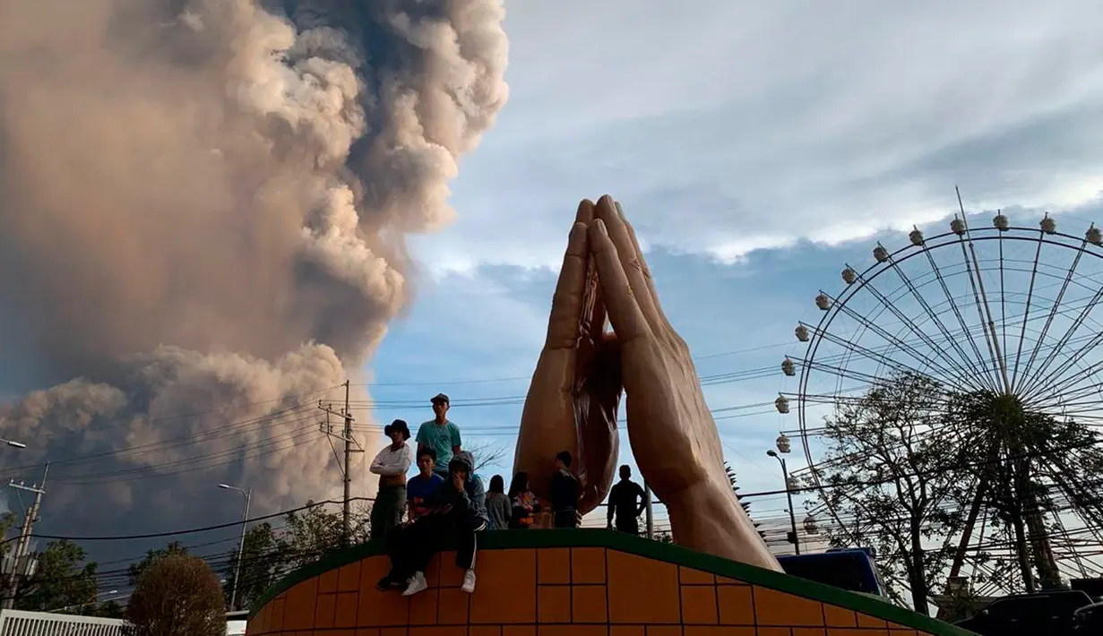 Sejumlah orang menyaksikan Gunung Api Taal erupsi di Tagaytay, Provinsi Cavite, Filipina, Minggu (12/1/2020). Ribuan orang yang tinggal di dekat gunung tersebut kemudian dievakuasi dari rumah mereka. (AP Photo/Bullit Marquez)
