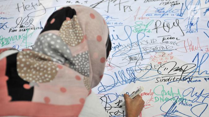 Pengunjung membubuhkan tanda tangan di atas spanduk raksasa saat car free day (CFD) di Bundaran HI, Jakarta, Minggu (22/7). Aksi ini merupakan dukungan masyarakat untuk kesuksesan pelaksanaan Asian Games 2018. (Merdeka.com/Iqbal Nugroho)