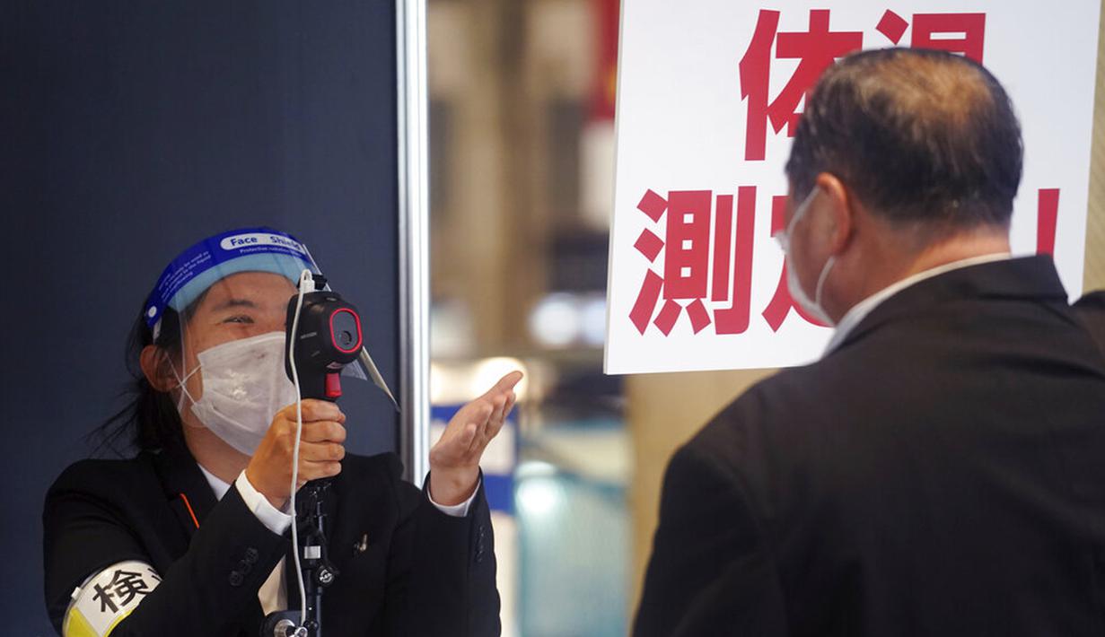 Seorang staf yang mengenakan masker untuk membantu mengekang penyebaran virus corona COVID-19 memeriksa suhu pengunjung di sebuah pamerang di Chiba, Tokyo, Jepan, Rabu, 28 Oktober 2020. Tokyo mengonfirmasi lebih dari 170 kasus COVID-19 baru pada 28 Oktober 2020. (AP Photo/Eugene Hoshiko)