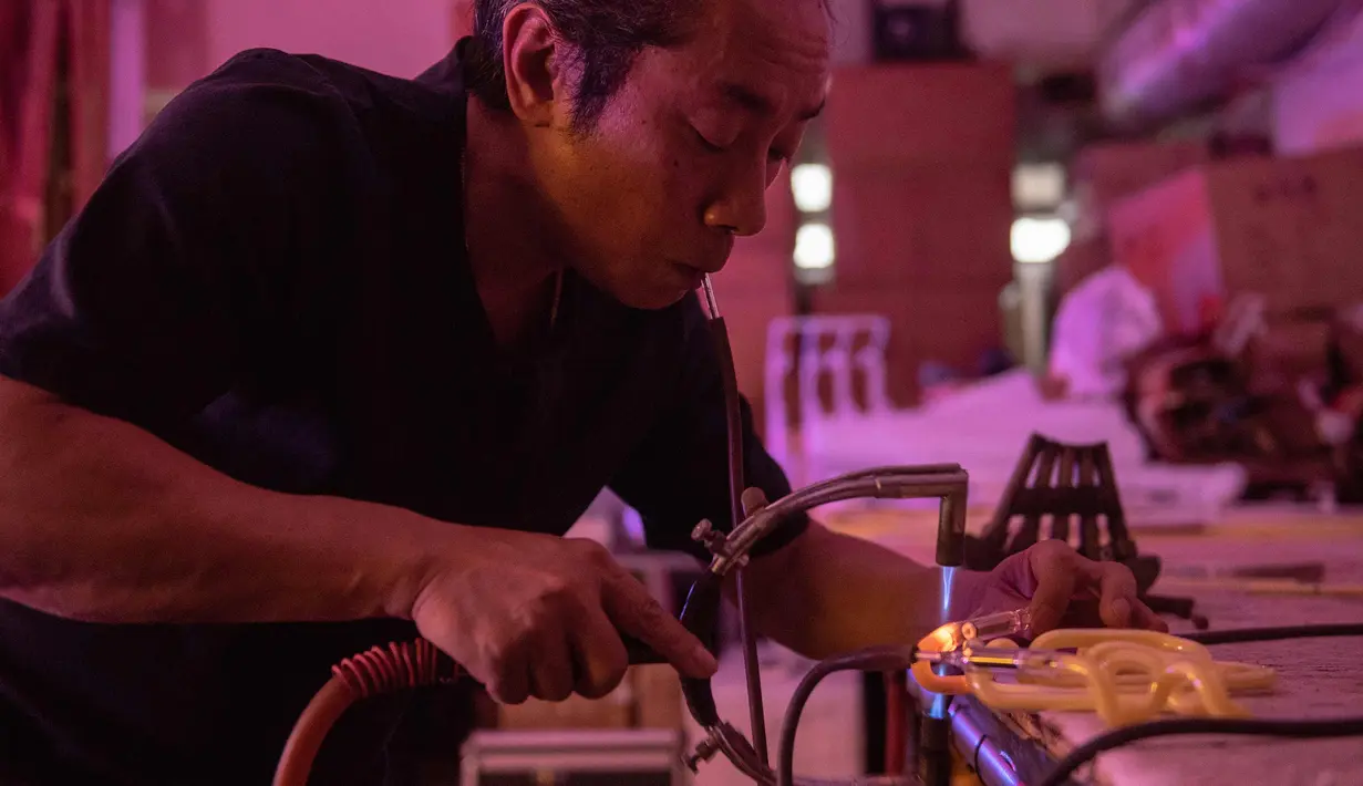 Wu Chi-kai mendemonstrasikan bagaimana membuat neon sign selama wawancara dengan AFP di Hong Kong (16/4). Wu Chi-kai merupakan salah satu pengrajin neon sign yang tersisa dari jenisnya di Hong Kong. (AFP Photo/Philip Fong)
