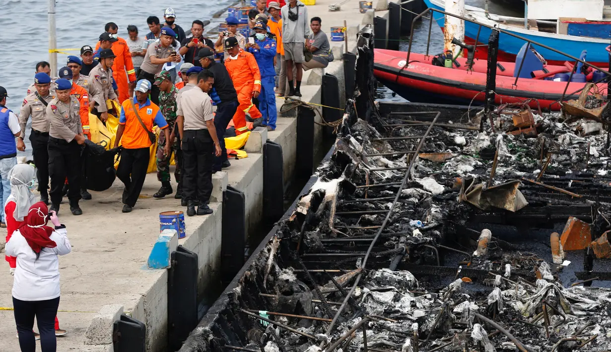 Petugas kepolisian bersama Tim SAR gabungan mengevakuasi kantong jenazah korban kapal Zahro Express yang terbakar, di Pelabuhan Muara Angke, Minggu (1/1). Sejumlah jenazah ditemukan dengan kondisi hangus terbakar dari kapal. (REUTERS/Darren Whiteside)