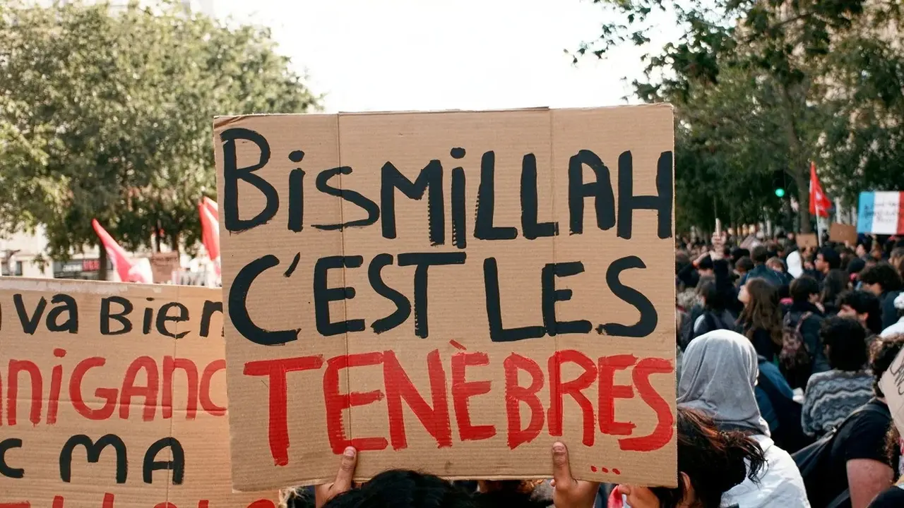 Seorang demonstran di Prancis mengangkat papan bertuliskan "Bismillah, C’est Les Ténèbres"