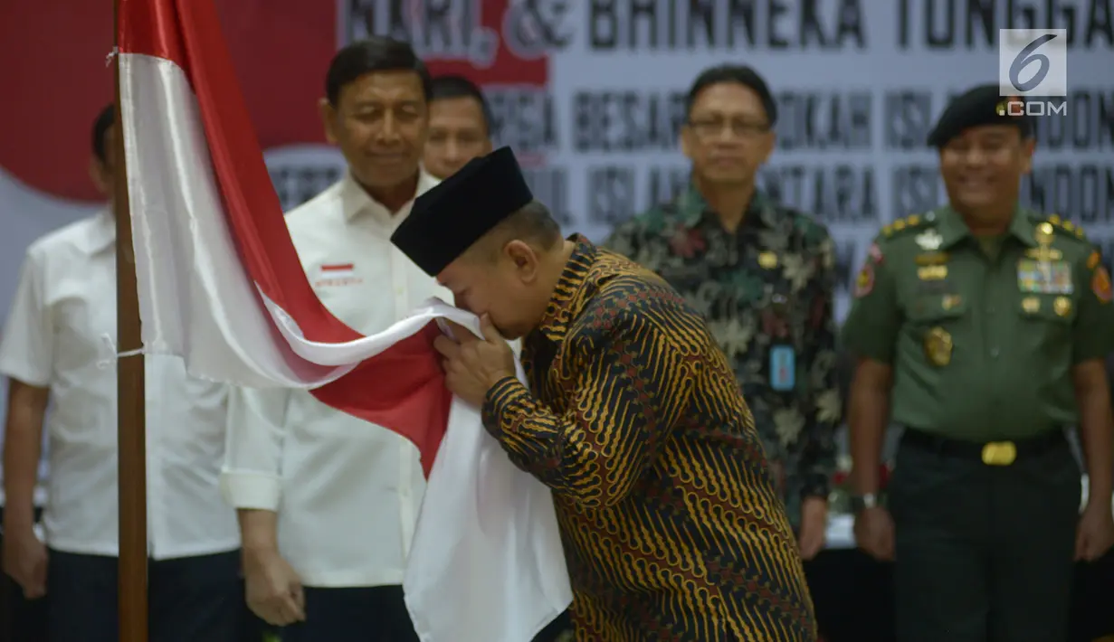 Anak pemimpin Darul Islam/Tentara Islam Indonesia (DI/TII) Sekarmaji Marijan Kartosuwiryo, Sarjono Kartosuwiryo mencium bendera Merah Putih saat pembacaan ikrar setia kepada Pancasila, UUD 45, NKRI dan Bhineka Tunggal Ika di Kemenko Polhukam, Jakarta, Selasa (13/8/2019). (merdeka.com/Imam Buhori)