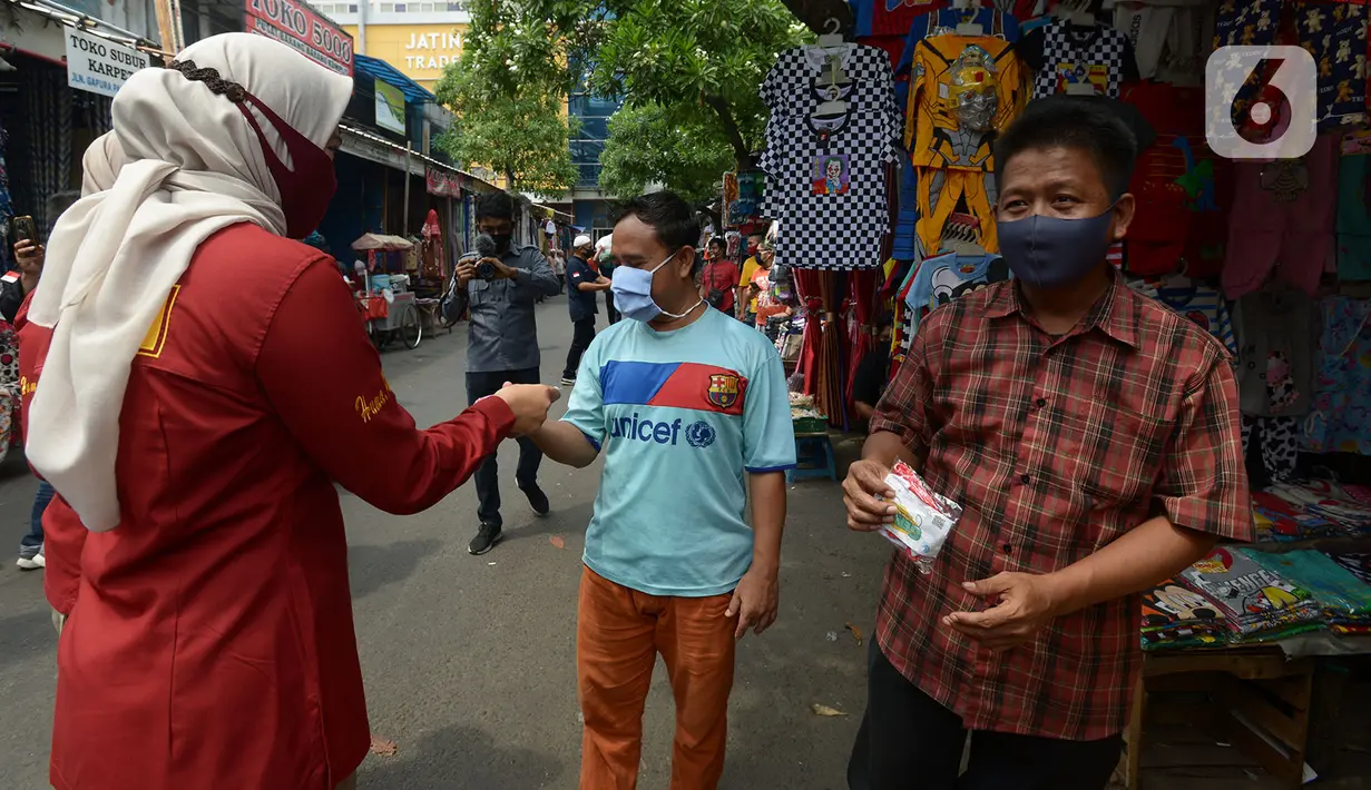 Petugas membagikan masker kepada warga di Pasar Jatinegara, Kamis (10/9/2020). Petugas gabungan terus melakukan himbauan untuk memakai masker dan membagikan masker di pasar tersebut. (merdeka.com/Imam Buhori)