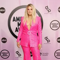 Meghan Trainor tampil cantik dengan setelan serba pink. Pasangan blazer dan celana berwarna pink yang berkilauan dipermanis dengan tambahan detail aksesori berupa kalung, cincin, dan bros tepat di tengah perut. Riasan wajahnya yang bernuansa merah muda pun tak terlihat medok, justru menyempurnakan keseluruhan tampilannya. Foto: Vogue.