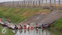 Warga mencuci pakaian di sungai yang menjadi pembatas di area Bandara Soetta, Tangerang (28/9/2015). Akibat kemarau panjang membuat pasokan air menjadi kering sehinga warga yang bermukim nekat menerobos pagar untuk mencuci. (Liputan6.com/Angga Yuniar)