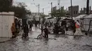 Warga Palestina berjalan di jalanan yang terendam banjir di samping kamp tenda sementara setelah hujan deras di Deir al-Balah, Jalur Gaza tengah, Selasa 25 November 2025. Banjir kembali menggenangi sebagian wilayah Deir al-Balah, Jalur Gaza tengah, pada Selasa 25 November 2025. (AP Photo/Abdel Kareem Hana)