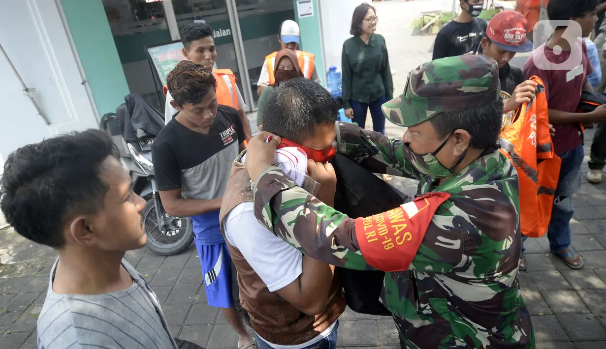 Tentara memakaikan masker kepada warga pelanggar PSBB yang terjaring Operasi Yustisi di BSD, Tangerang Selatan, Banten, Rabu (16/9/2020). Sanksi sosial lari sejauh 800 meter diberikan kepada warga pelanggar PSBB untuk memberikan efek jera. (merdeka.com/Dwi Narwoko)