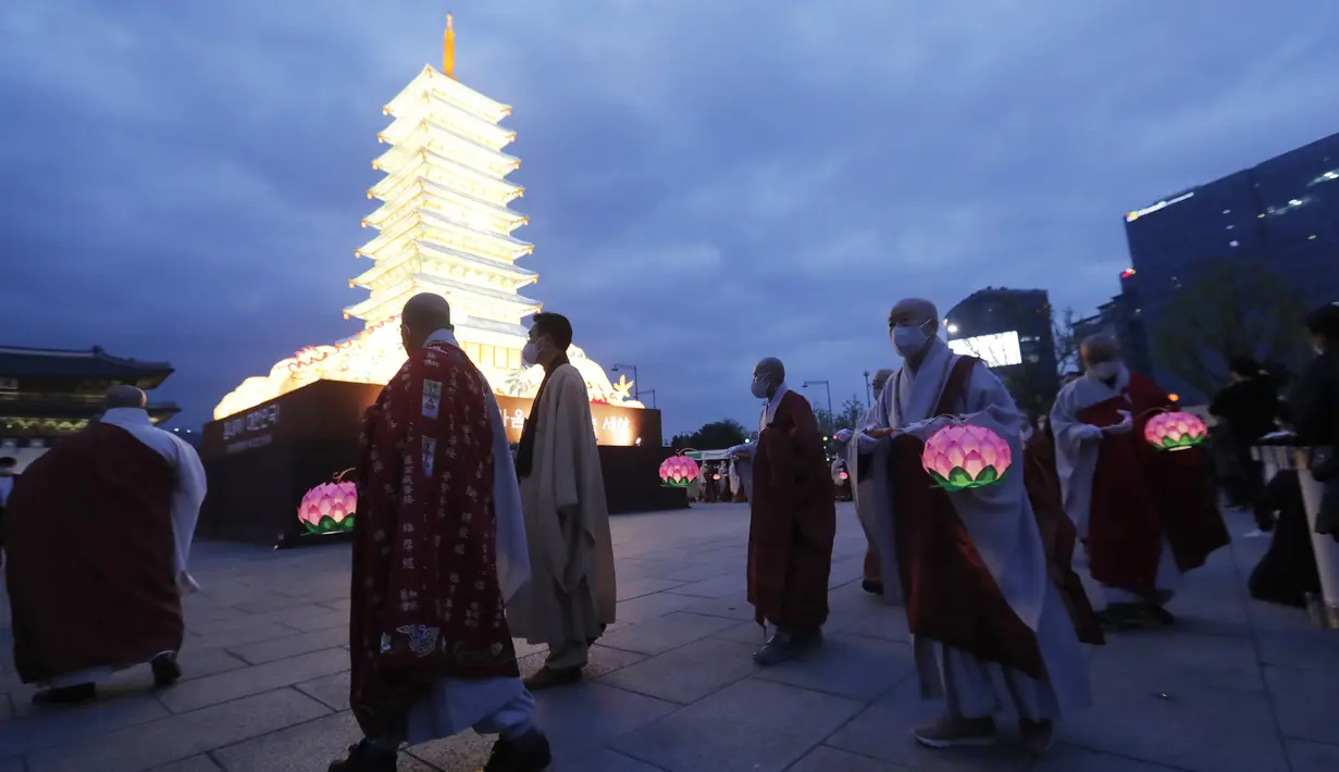 Para biksu yang mengenakan masker berjalan di sekitar menara lentera berbentuk pagoda saat merayakan ulang tahun Buddha di Gwanghwamun Plaza, Seoul, Korea Selatan, Kamis (30/4/2020). Ulang tahun Buddha kali ini dirayakan di tengah pandemi virus corona COVID-19. (AP Photo/Ahn Young-joon)