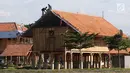 Pekerja menyelesaikan proyek pembangunan Perkampungan Budaya Betawi di tengah Setu Babakan, Jakarta, Kamis (3/1). Kawasan tersebut nantinya akan dihiasi dengan berbagai bangunan bertema Betawi. (Liputan6.com/Immanuel Antonius)