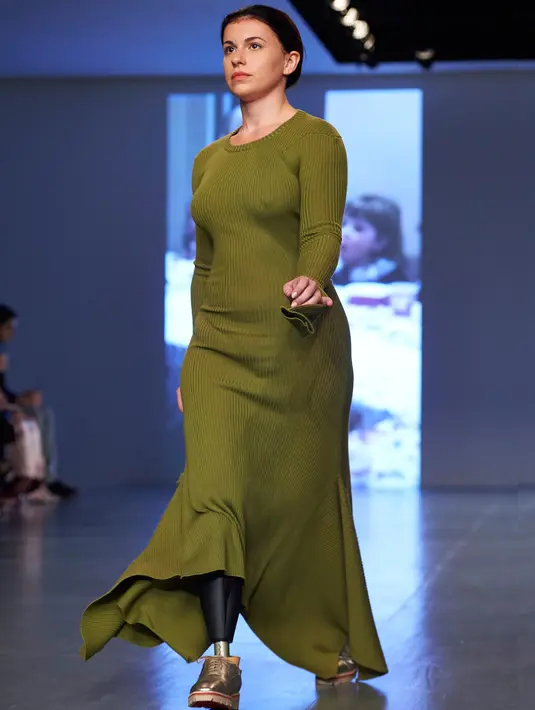 Model dengan kaki palsu melenggang di catwalk menampilkan koleksi Spring/Summer 2018 Teatum Jones selama London Fashion Week, 15 September 2017. Model tersebut memakai gaun panjang warna hijau lumut dan kaki palsu. (NIKLAS HALLE'N/AFP)