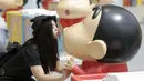 Seorang wanita berpose mengikuti gaya Crayon Shinchan saat berfoto di pameran Joy City, Beijing (5/5/2015). Lima puluh model karakter kartun Jepang dalam berbagai pose dan ekspresi dihadirkan dipameran tersebut. (REUTERS/Jason Lee)