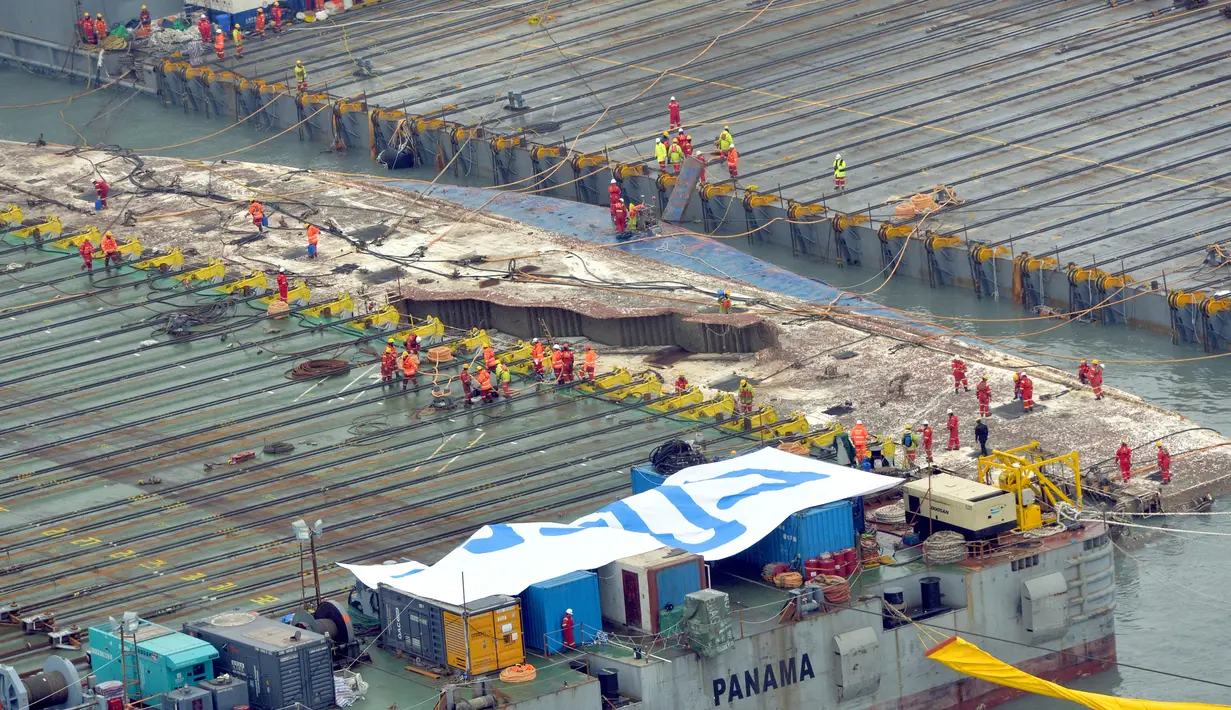 Bagian sisi kanan bangkai feri Sewol mulai terlihat di antara dua tongkang raksasa di pulau barat daya Jindo, Korea Selatan, Kamis (23/3). Proses evakuasi diperkirakan memakan biaya sekitar hampir satu triliun rupiah. (Park Gyung-woo/Hankookilbo via AP)