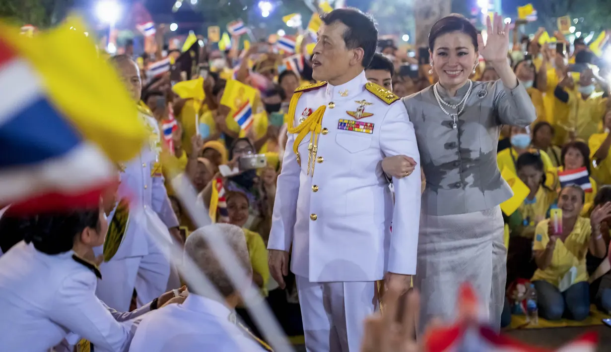 Raja Maha Vajiralongkorn dan Ratu Suthida melambaikan tangan ke pendukungnya di Bangkok, Thailand, Minggu (1/11/2020). Di bawah tekanan yang meningkat dari pengunjuk rasa yang menuntut reformasi pada monarki, Raja dan Ratu Thailand bertemu dengan ribuan pendukungnya. (AP Photo/Wason Wanichakorn)