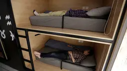 Dua pegawai terlihat tidur siang ditempat tidur pada jam istirahat di kantornya di Beijing, China, (21/4). Sejumlah kantor di Beijing menyediakan ruangan kecil yang dikhususkan untuk tidur siang para pegawainya. (REUTERS/Jason Lee)