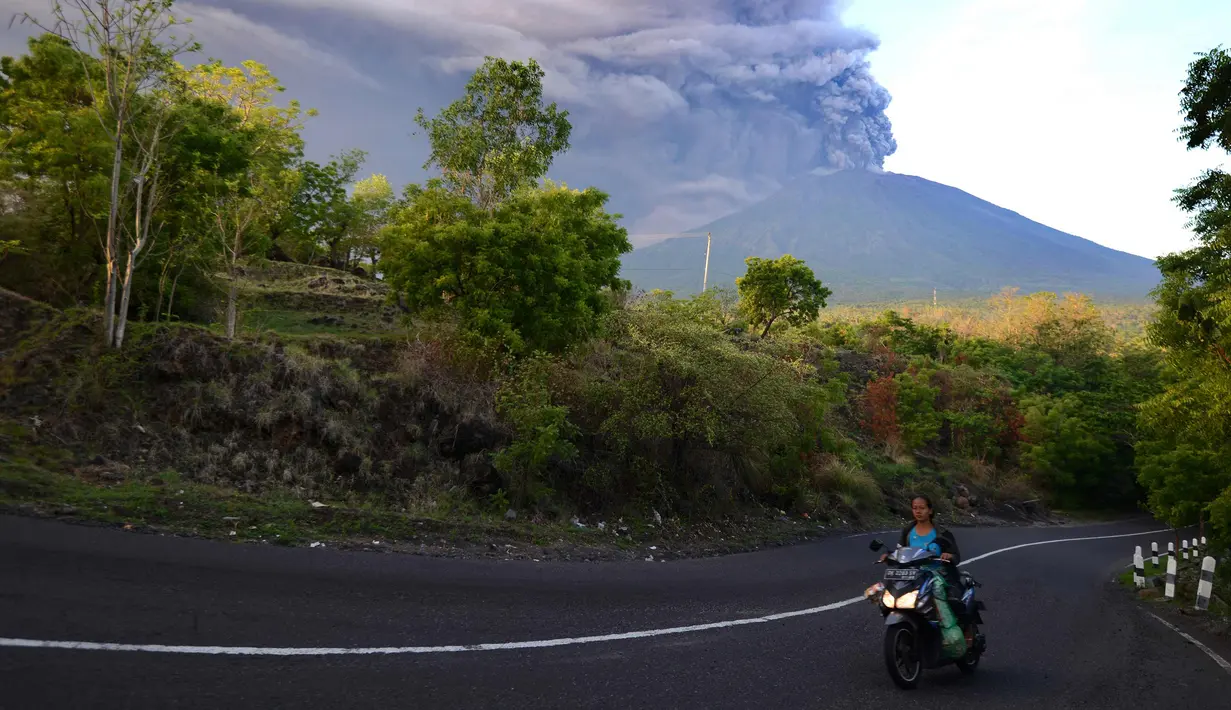 Warga mengendarai motor saat Gunung Agung Mengeluarkan abu vulkanik di Kecamatan Kubu, Karangasem, Bali, Minggu (26/11). Semburan asap dan abu vulkanik Gunung Agung mencapai ketinggian 1.500 meter dari puncak Gunung Agung. (AFP/Sonny Tumbelaka)