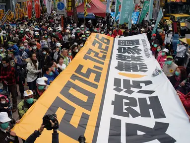 Demonstran mengunakan masker membawa spanduk raksasa saat unjuk rasa menuntut pemerintah Taiwan dalam pengurangan polusi udara di Taipei (26/12). Ratusan warga berbaris di jalan-jalan memprotes kebijakan energi pemerintah. (AFP PHOTO/Sam Yeh)