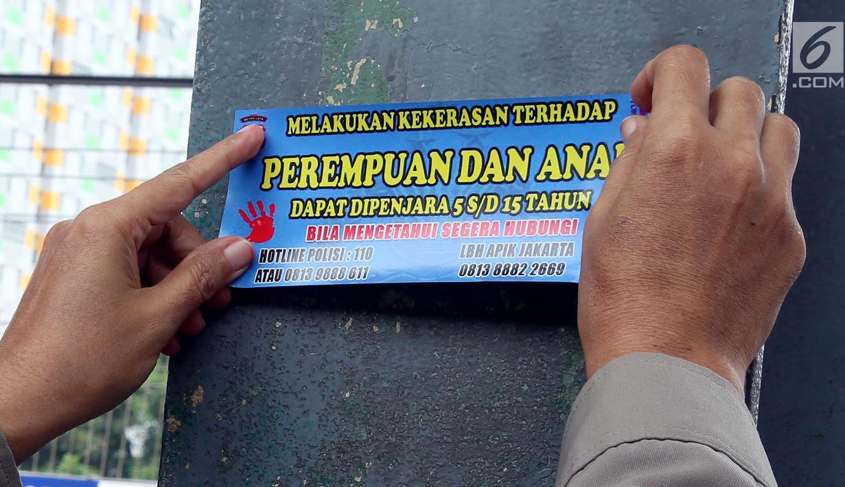 Petugas dari Polda Metro Jaya menempelkan stiker informasi pengaduan kekerasan di sekitar Stasiun Tanah Abang, Jakarta, Kamis (21/12). Stiker itu juga berisi informasi hukuman bagi pelaku tindak kekerasan pada wanita dan anak. (Liputan6.com/JohanTallo)