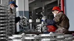 Dua pekerja mengecek kondisi pelek di pabrik pembuatan pelek sepeda motor di Jinhua, Provinsi Zhejiang, China (14/1). (AFP Photo/China Out)