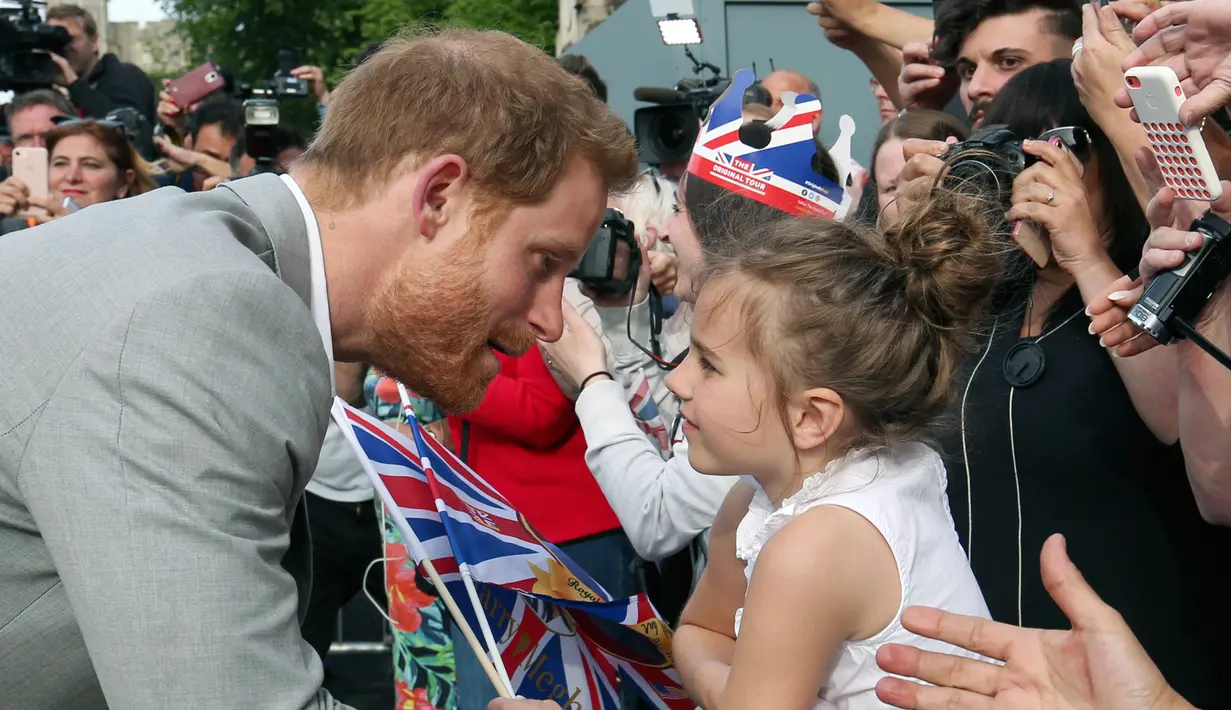Pangeran Harry menyapa seorang bocah pemberi selamat di luar Kastil Windsor, Inggris, Jumat (18/5). Pangeran Harry dan Meghan Markle akan menikah pada 19 Mei 2018. (Ben Birchall/PA via AP)