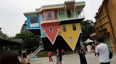 Pengunjung berpose di depan rumah terbalik di Huashan Creative Park, Taipei, Taiwan, (7/4). Sekelompok arsitek Taiwan membangun rumah seluas 300 meter yang menghabiskan dana US$ 600.000 dalam kurun waktu 2 bulan. (REUTERS/Tyrone Siu)