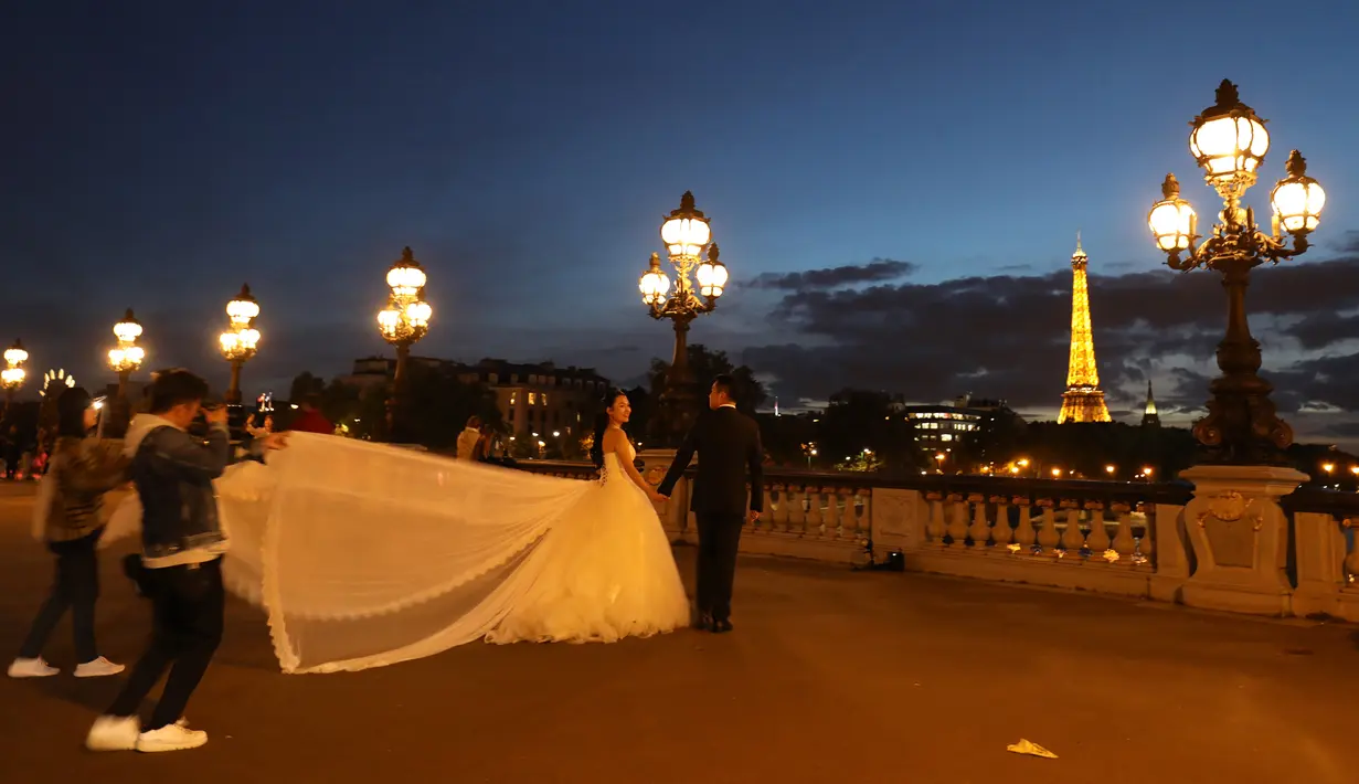 Sepasang calon pengantin dekat Menara Eiffel dari jembatan Alexandre III di Paris, 3 Oktober 2017. Jembatan yang terkenal dengan desain dan ornamen-ornamennya khas Eropanya ini berada tepat di atas Sungai Seine (AFP PHOTO / LUDOVIC MARIN)