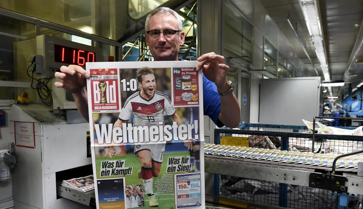 Andreas Schenk, salah satu petugas percetakan surat kabar "Bild", menunjukkan halaman depan yang berisi foto selebrasi pemain tengah Timnas Jerman, Mario Goetze, (14/7/2014). (REUTERS/Fabian Bimmer)