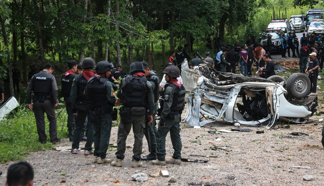 Sejumlah personel militer berkumpul di lokasi ledakan sebuah bom yang disembunyikan di bawah tanah di provinsi Yala, selatan Thailand, Jumat (23/9). Setelah meledakkan bom dari jarak jauh, pelaku menembaki polisi dari balik pepohonan. (KATAWUT CHUM/AFP)